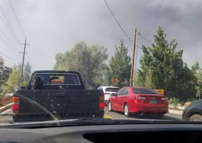 A photo of cars stopped with the smoke overhead.
