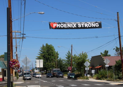 A photo of a street with a banner that reads "Phoenix Strong"